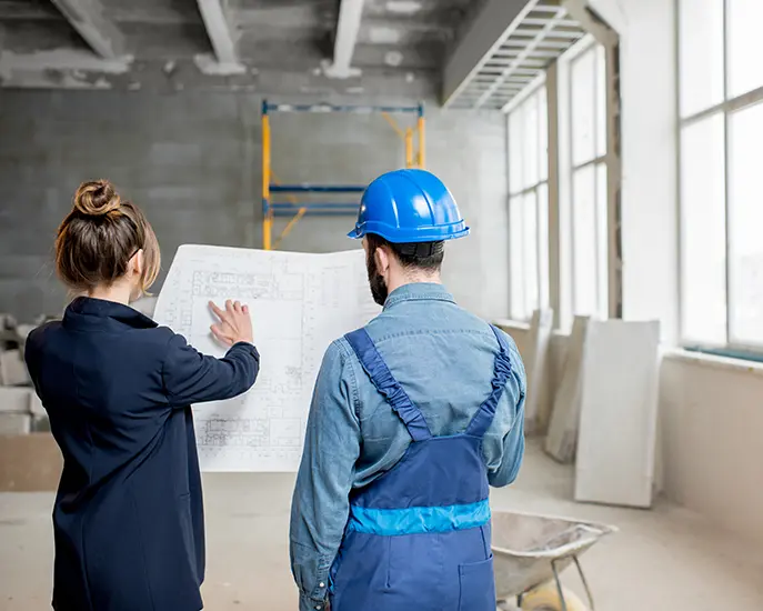 Architect and construction worker reviewing blueprints for a commercial remodeling project.