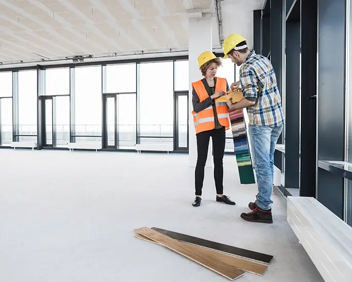 Two construction workers discussing flooring options for a commercial remodeling project.