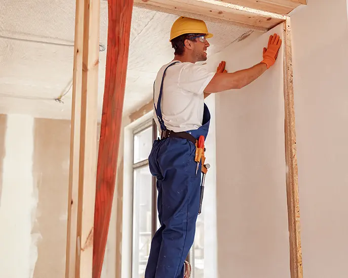 Construction worker installing drywall in a home renovation project.