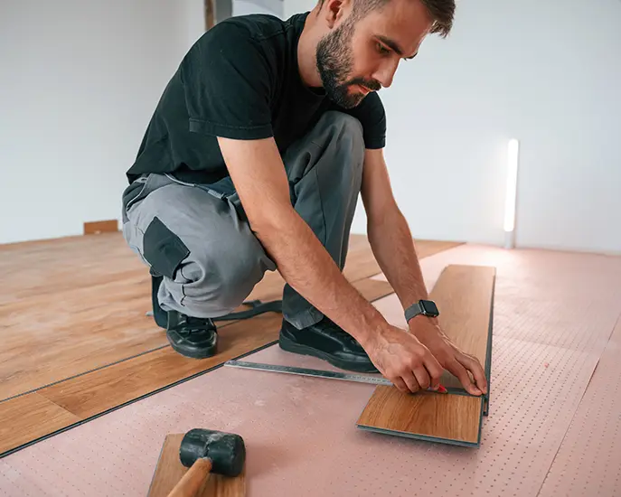 Expert flooring installer measuring and laying vinyl plank flooring.