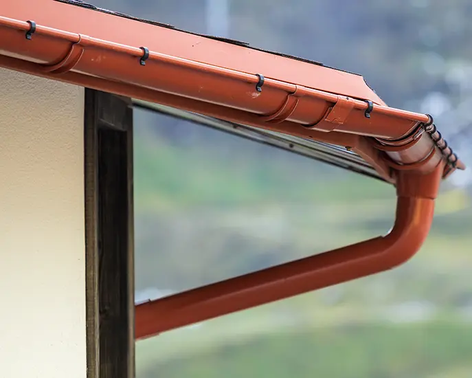 Red gutter system installed on a roof for effective water drainage.
