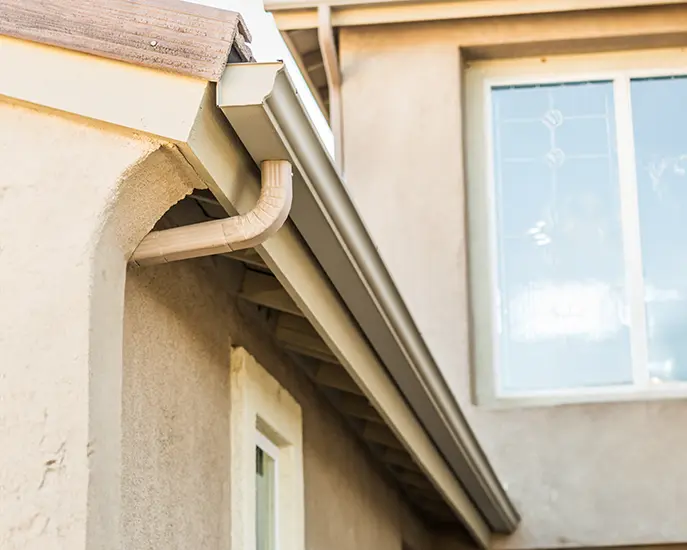 Newly installed beige gutter system on a home, ensuring proper water drainage.