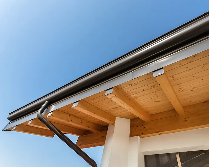 Newly installed black gutter system on a modern wooden roof structure.