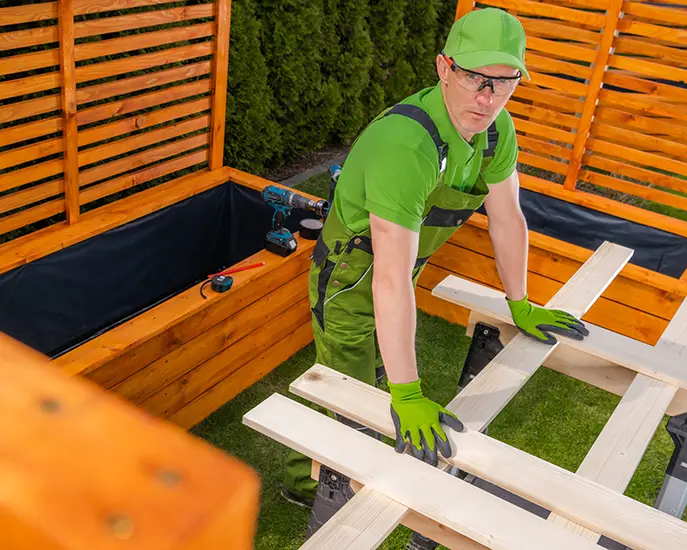 Worker building a custom wooden outdoor structure for a home improvement project.