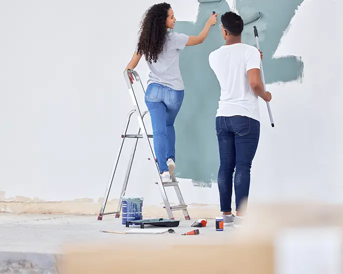 Couple painting a wall together during a home renovation project.