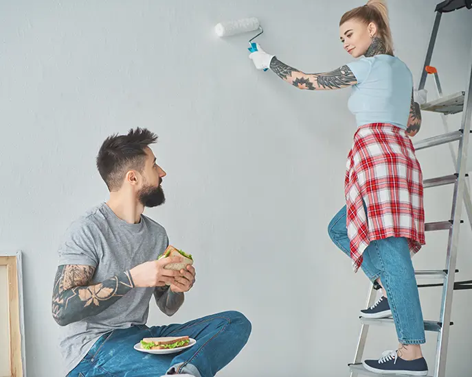 Couple painting a wall together during a home renovation project.