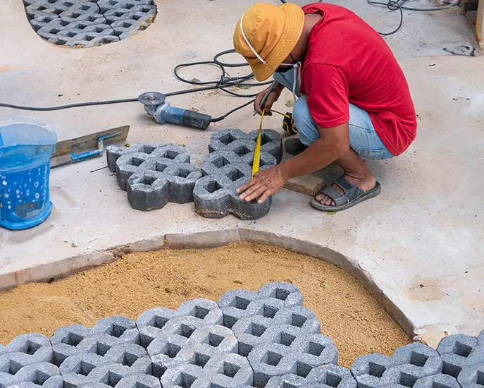 Worker measuring and cutting stone pavers for custom installation.