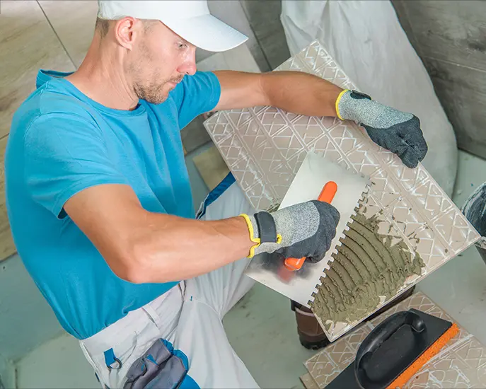 Professional worker applying adhesive to a tile during a tile installation project.